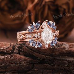 an engagement ring set with blue and white stones on top of a piece of wood