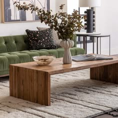 a living room with a green couch and coffee table in front of a painting on the wall