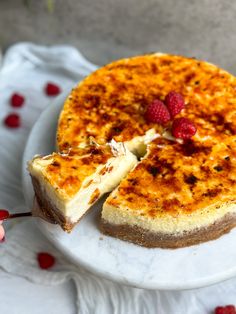 a cheesecake with raspberries is cut into slices on a white cake plate