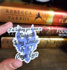 a person holding up a sticker in front of some books