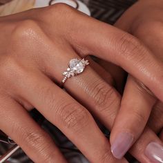 a woman's hand with a diamond ring on her finger and the other hand holding an engagement ring