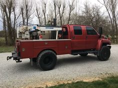 a red truck parked on top of a gravel road