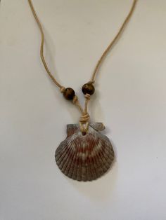 Handmade sea shell necklace crafted with a scallop shell, hemp cord, and wooden beads. Necklace With Shells Diy, Homemade Shell Necklace, Scallop Shell Necklace, Hawaiian Shell Jewelry, Handmade Shell Necklace, Beaded Shell Necklace, Sea Shell Necklace Diy, Cord Necklace Diy, Diy Shell Jewelry