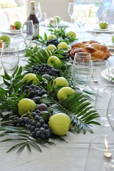 the table is set with fruit and greenery