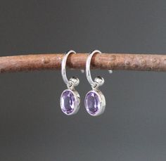 "Sweet faceted bright Purple Amethyst oval stones are bezel set in simple silver charms.  These dangle from delicate silver post hoops. The charms are removable and the hoops can be worn by themselves or with different charms. Wonderful earrings to complete any outfit for daytime or evening. A perfect gift for a young girl! Amethyst bezels: 6x8mm  Silver post hoop: 1x10mm Total length of earrings: 3/4\" Length is approximate.  All silver is sterling. As the owner, maker, designer, and curator of Oval Gemstone Hoop Earrings For Gift, Oval Gemstone Hoop Earrings As Gift, Hell Lila, Earrings Aesthetic, Hoop Earrings Silver, Earrings Purple, Earrings 3, Earrings Small, Bright Purple