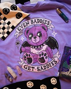 Upgrade your wardrobe with our Comfort Colors T-Shirt featuring the "Even Baddies Get Saddies" design. This graphic t-shirt combines comfort with edgy style, perfect for those who appreciate alt fashion and gothic art. 

The design includes a crying gothic demon purple bear with a wilting flower, choke collar, and black demon wings, creating a striking look. Ideal for casual outings or making a bold fashion statement, this shirt is a must-have for your collection. Edgy Outfit, Edgy Style, Alt Fashion, Comfort Colors Tee