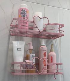 a pink shelf holding various personal care items in a white tiled shower stall with marbled walls