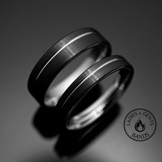 two wedding bands are sitting on top of each other in front of a black and white background