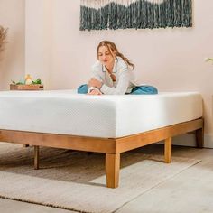 a woman sitting on top of a bed next to a plant and potted plants