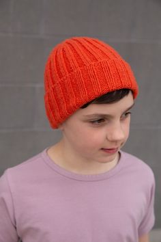 a young boy wearing an orange knitted hat