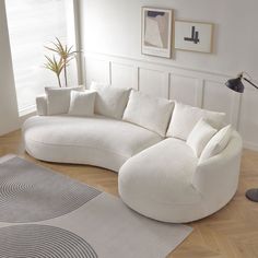 a living room with a large white couch and rugs on the wooden flooring