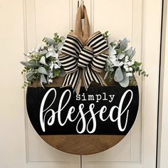 a wooden sign that says simply blessed hanging on a door with a bow and flowers