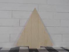 a piece of wood sitting on top of a checkered blanket next to a white brick wall