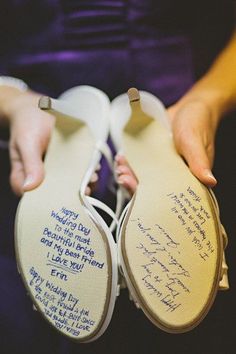 a pair of shoes with writing on the soles are held by someone's hands