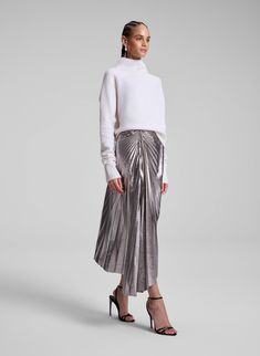 The Tracy Skirt is crafted from our lightweight metallic vegan leather in a silver hue. This midi silhouette features an asymmetrical hem with starburst pleating and ruched detailing at the hip, offering a modern, high-shine update to a classic style. Shop Bottoms. Styling Tip: Offset with a sumptuous knit or a crisp button-down for a balanced, elevated look. 50th Clothing, Vegan Leather Skirt, Heel Accessories, Sneaker Heels, Asymmetrical Hem, Denim Pant, Asymmetric Hem, Sweater Skirt, Sweater Jacket