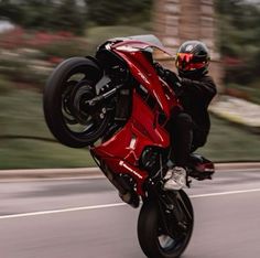 a man riding on the back of a red motorcycle