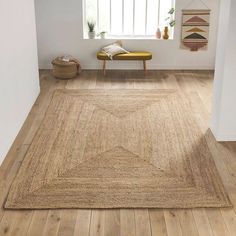 an area rug in the middle of a room with wooden flooring and white walls