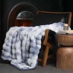 a chair with a blanket on it next to a fire place