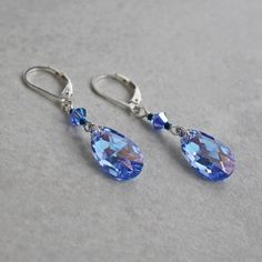 "Light blue crystal earrings are made with faceted light sapphire crystal teardrops with an AB coating on the back, which reflects light and color. They are accented with sapphire crystals and dark metallic blue seed beads. Earrings dangle 1\" from sterling silver ear wires. ❖  Crystal Passions crystal teardrops - 16mm ❖  Crystal Passions crystal bicones - 4mm ❖  glass seed beads ❖  sterling silver Earrings shown are on lever backs.  All earring types are sterling silver with the exception of cl Blue Briolette Jewelry For Party, Sapphire Teardrop Crystal Earrings For Formal Occasions, Elegant Blue Faceted Crystal Earrings, Sapphire Crystal Drop Earrings, Blue Crystal Drop Earrings, Faceted Crystal Teardrop Earrings, Blue Drop Crystal Earrings, Nickel-free Blue Crystal Earrings For Formal Occasions, Blue Crystal Teardrop Dangle Earrings