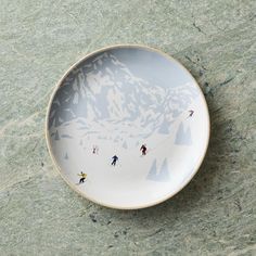 a plate with skiers on it sitting on the ground in front of a mountain