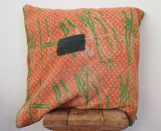 an orange and green pillow sitting on top of a wooden stand