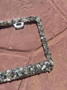 a piece of metal sitting on top of a red rock covered in lots of small rocks