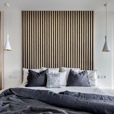 a large bed sitting under two lamps next to a wooden headboard with black and white stripes on it