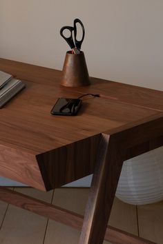 a wooden table topped with a phone and scissors