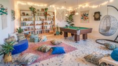 a living room with a pool table and lots of pillows on the floor in front of it