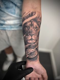 a man's arm with a lion and compass tattoo on the left side of his arm