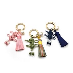 three key chains with tassels on them