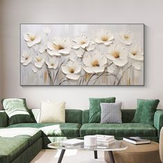 a living room with green couches and large white flowers on the wall above it