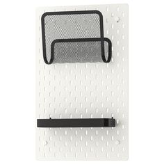 a white pegboard with a black shelf on it and a metal mesh hanging from the wall