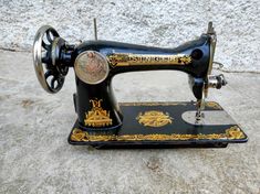 an old black sewing machine sitting on top of a cement floor next to a wall