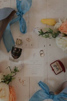 an assortment of wedding rings and flowers on a table with blue satin ribbons around them