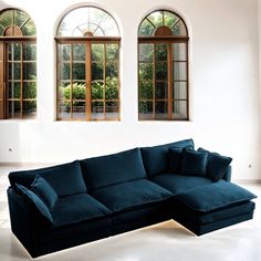 a large blue couch sitting in front of three windows