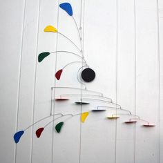 a metal wall sculpture with multicolored circles hanging from it's sides on a white wall