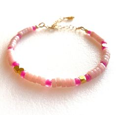 Natural pink opal heishi rondelles beaded with hot pink Japanese seed beads and 24k gold vermeil faceted cubes. Dainty beaded bracelet closes with 14k gold fill spring ring and 1 1/2 inch extension. Ones size adjustable from 6 1/4 to 8 inches. Pink Bohemian Beaded Bracelets With Heart Beads, Bohemian Pink Beaded Bracelets With Heart Beads, Pink Heishi Beads Jewelry With Spacer Beads, Pink Rondelle Beaded Bracelets, Hand-strung, Pink Rondelle Beaded Bracelets, Pink Hand-strung Rondelle Beaded Bracelets, Pink Rondelle Bracelets With Faceted Beads, Pink Rondelle Beaded Bracelets As Gift, Pink Rondelle Beaded Bracelets For Gifts