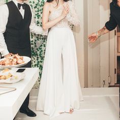 a man and woman standing next to each other in front of a table with food on it