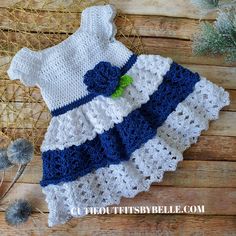 a crocheted baby dress with flowers on the bottom and blue trimmings