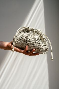 a hand holding a small white bag in it's palm