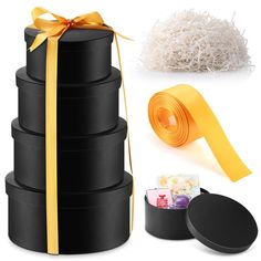 a stack of black boxes with yellow ribbon and some candies in the bottom one