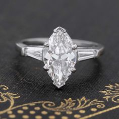 Marquise cut diamonds, while currently making a serious comeback, have always been a personal fave of mine - I love the sexy shape, the flattering outline, and just how unique a cut it is. This particular solitaire showcases a 1.79ct chubbier marquise as its center stone, its broad and chunky facets acting like a mirror and picking up all the colors and light from its surrounding, throwing it back to the wearer gleefully. Flanked by approx .21ctw of tapered baguettes on the shoulders, the ring w Modern Mens Rings, Art Jewelry Earrings, Antique Watches, Marquise Cut Diamond, Antique Engagement, Mens Band, Vintage Band, Perfect Engagement Ring, Cut It