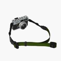 a camera with a green strap attached to it's body, on a white background