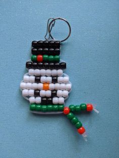 a beaded christmas tree ornament is hanging on a blue surface with two green, white and red beads