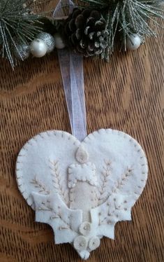 a heart shaped ornament hanging on a table with pine cones and evergreen branches