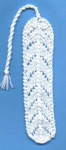 a white crochet bookmark with tassels on it and a blue background