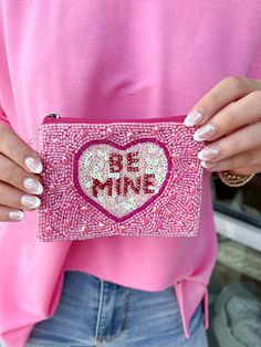 a woman is holding a pink purse with sequins and the words be mine written on it