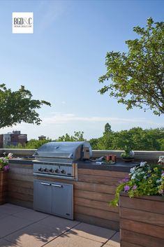 an outdoor kitchen with grill, sink and potted plants on the roof top deck