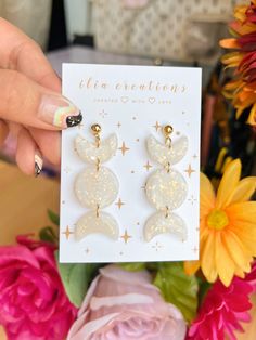 a person holding up a card with two earrings on it